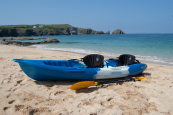 Feelfree blue kayak with two paddles and seats on a sandy beach